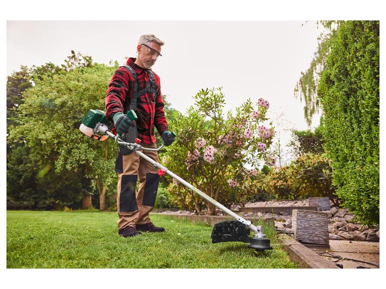 Een man gebruikt een bosmaaier om onkruid te verwijderen.