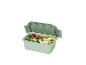 Boîte à lunch verte avec compartiments, remplie de brocoli, de raisins et de pâtes.