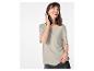Femme souriante en t-shirt gris clair et jean foncé, main dans la poche.