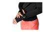 Femme en haut noir à manches longues et leggings orange, regardant une montre connectée
