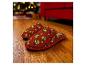 Pantoufles rouges à motif Grinch sur un parquet, avec des lumières de Noël en arrière-plan.