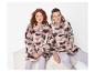 Deux personnes en sweats à capuche moelleux camouflage rose et gris, assises sur un banc blanc.
