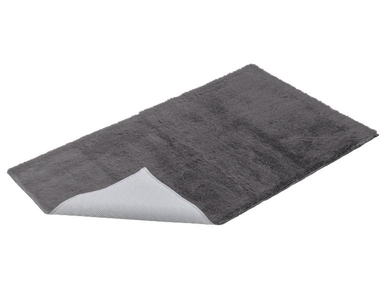Grijze pluizige badmat met antislip onderkant, schuin weergegeven.