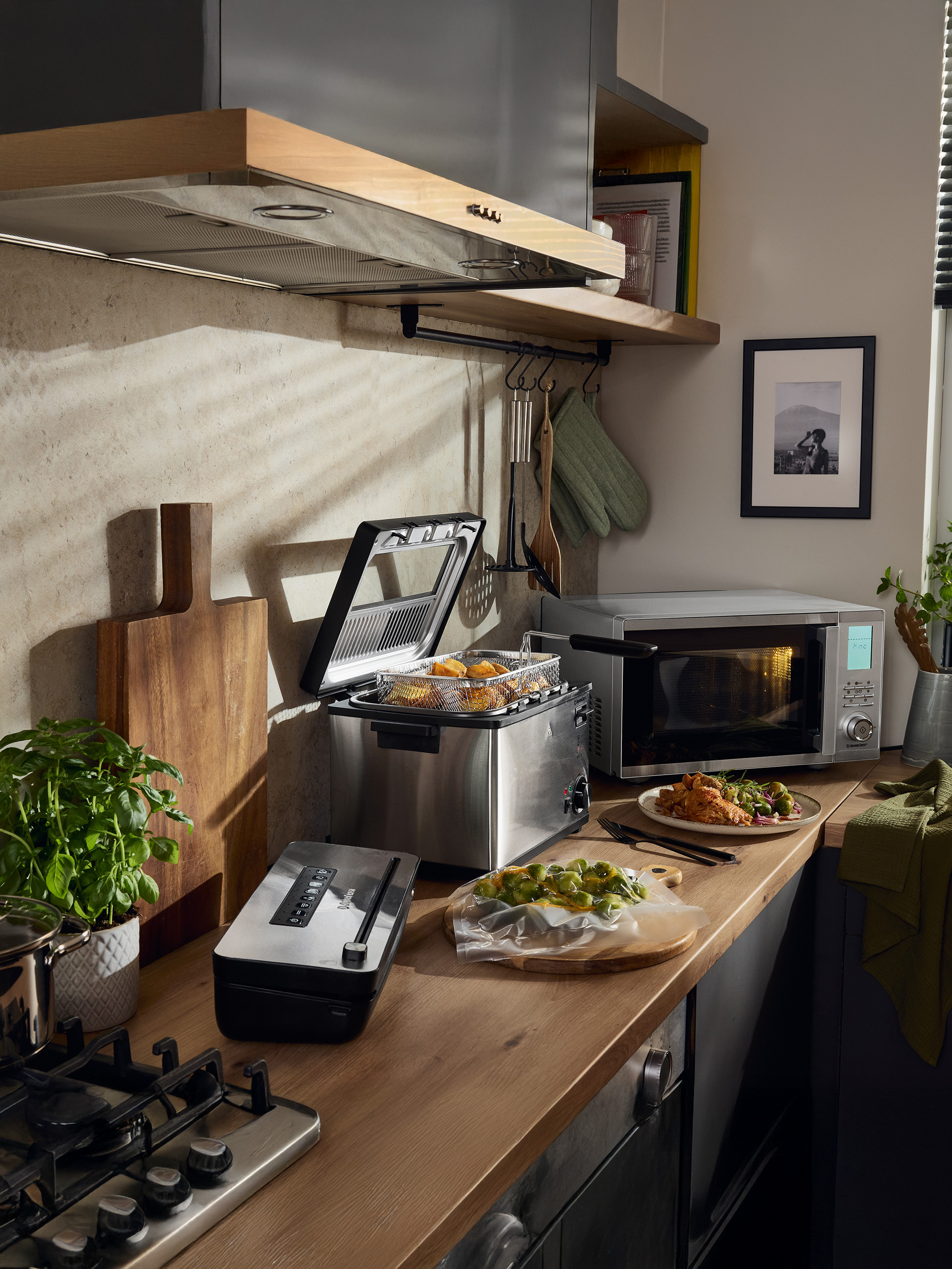 Cuisine avec friteuse, micro-ondes SilverCrest, machine sous vide et plat cuisiné.