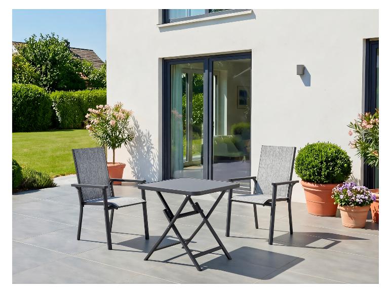 Terrasse extérieure avec une table pliante gris foncé et deux chaises assorties, entourée de plantes en pot.