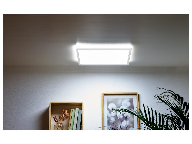 Plafonnier LED carré éclairant une pièce avec une étagère et une plante.