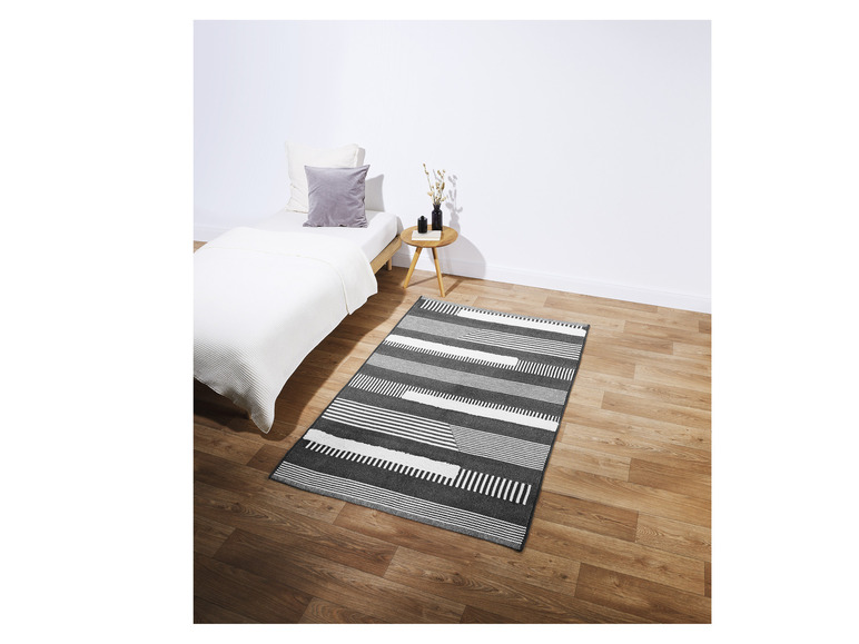 Een zwart-wit gestreept tapijt in een slaapkamer.