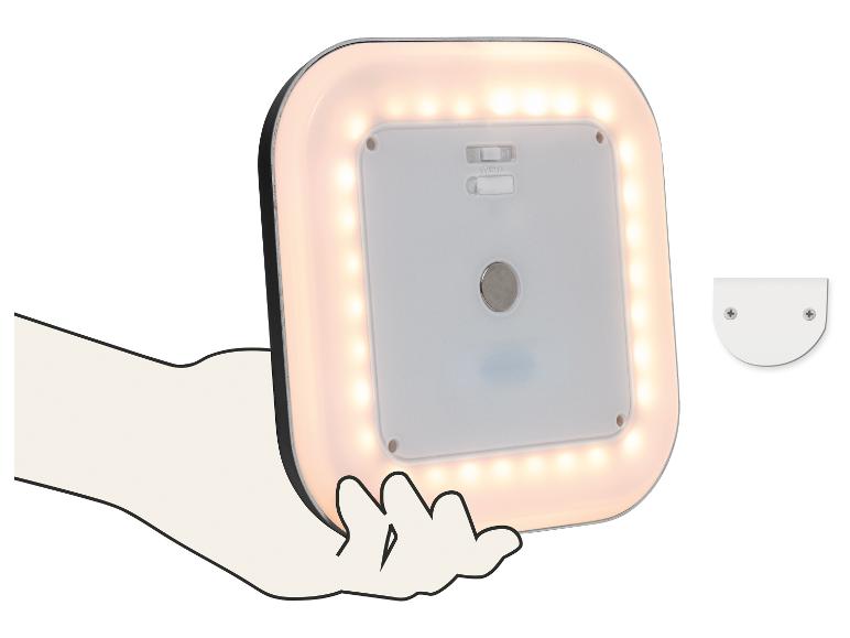 Lampe LED carrée à lumière blanc chaud, tenue à la main, avec un support de montage à côté.