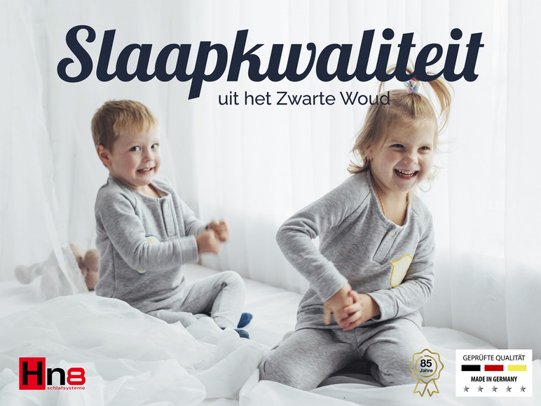 Twee kinderen in grijze pyjama's slapen in bed. Advertentie van Hne Schlafsysteme.