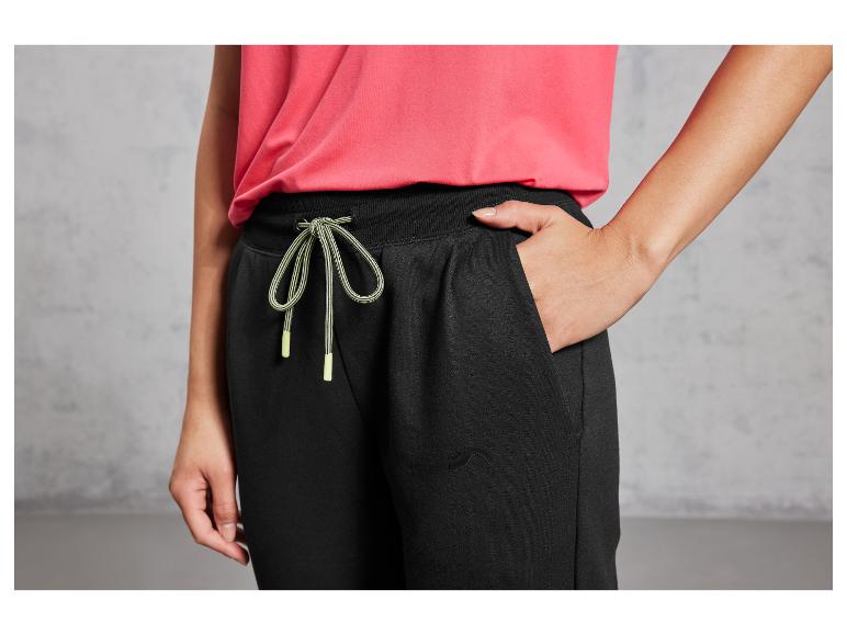 Zwarte joggingbroek met groene veters en een roze T-shirt.