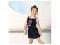 Een meisje draagt een blauwe jumpsuit met de tekst 'Summer Beach Ocean Wave'.