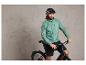 Een man met een helm en een jas rijdt op een zwarte fiets.