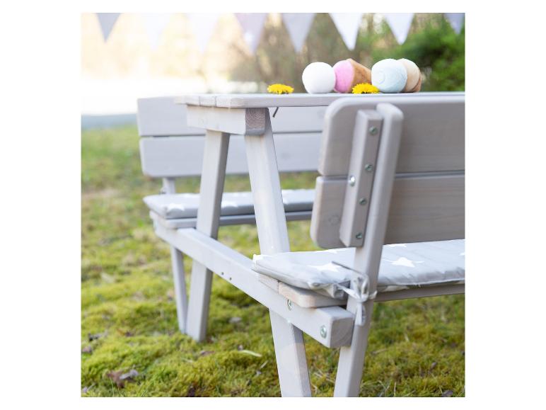 Table de pique-nique grise avec bancs et coussins, décorée de glaces jouets et de pissenlits.