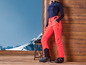 Vrouw draagt ski-kleding met felroze broek en zwarte ski-laarzen.