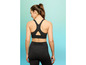 Een vrouw draagt een zwarte sportbeha en leggings.
