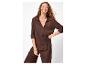 Femme en chemise et pantalon marron, avec des bijoux dorés, souriante.