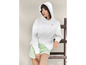 Een vrouw draagt een witte hoodie met de tekst 'Grand Polo' en groene shorts.