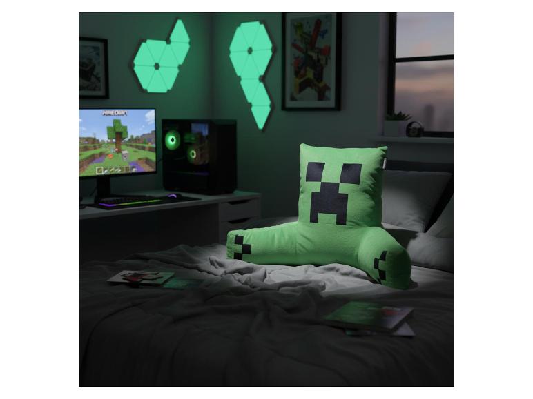 Gamingkamer met groen karakterkussen op bed, computeropstelling en geometrische wandlampen.