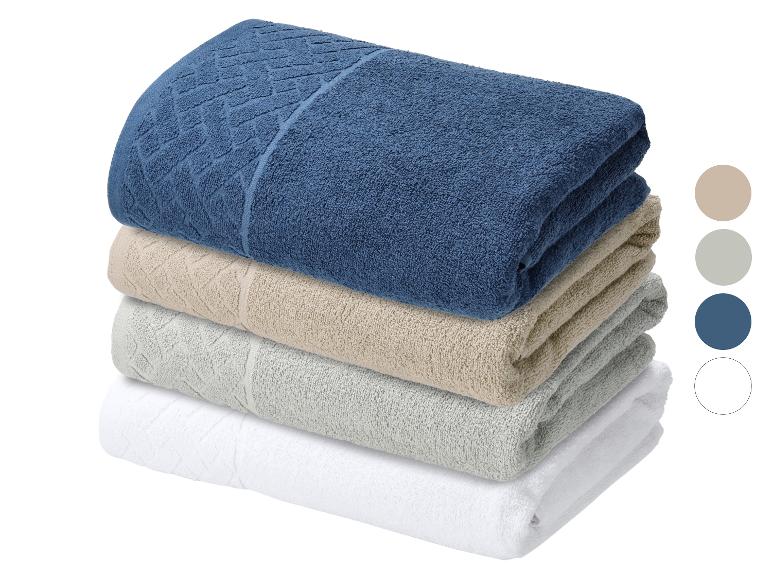 Pile de quatre serviettes de couleurs bleue, beige, grise et blanche.