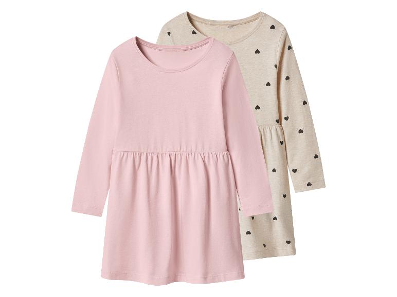 Deux robes à manches longues pour enfants, une rose unie et une beige à cœurs noirs.