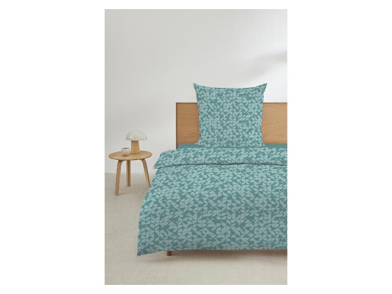 Dekbedovertrek en kussensloop met geometrisch patroon in turquoise en grijs, op een bed met houten hoofdbord.