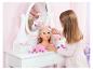 Fille coiffant les cheveux d'une poupée de coiffure sur une coiffeuse blanche.