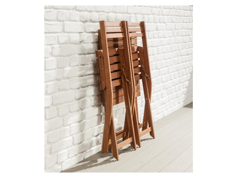 Twee houten vouwstoelen tegen een witte bakstenen muur
