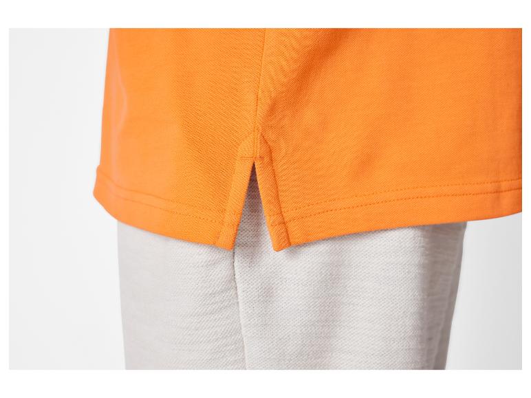 Oranje polo shirt met grijze broek.