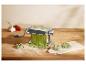 Pastamachine met verse groene pasta, knoflook en tomaten op een houten tafel.