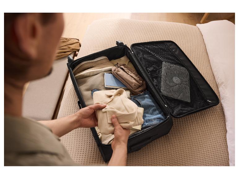 Un homme range ses vêtements dans une valise noire ESMARA® sur le lit.