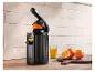 Zwarte SilverCrest citruspers, glas sinaasappelsap en sinaasappels op houten snijplank.