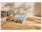 Récipient transparent avec des raisins sur une table en bois, pots en arrière-plan.