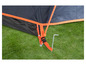 Een oranje tentstok met een gesp bevestigd aan een zwarte tent op gras.