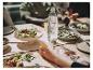 Une bouteille Sodastream d'eau pétillante sur une table avec de la nourriture et des gens.
