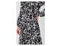 Une robe maxi noire à imprimé géométrique et ceinture.