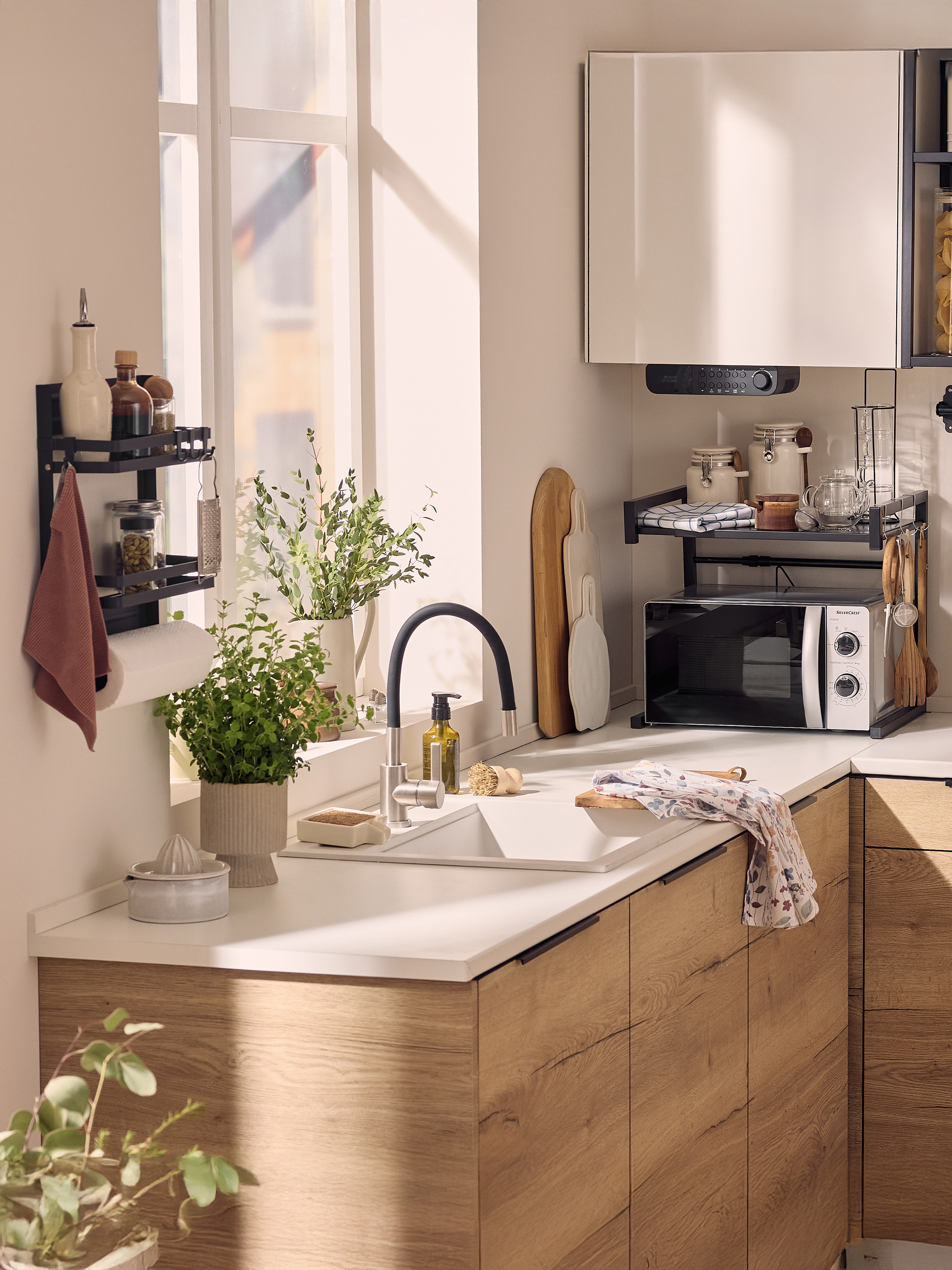 Moderne keuken met spoelbak, magnetron, wandplanken en groene planten.