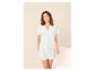 Femme en pyjama blanc broderie anglaise, avec chemise à manches courtes et short.