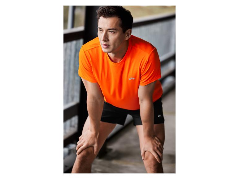 Man in een oranje T-shirt en zwarte shorts van het merk Craft.