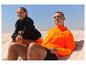 Sportkleding: oranje jas en zwarte trui op het strand.