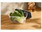Bok choy frais dans un récipient transparent sur un comptoir en bois.
