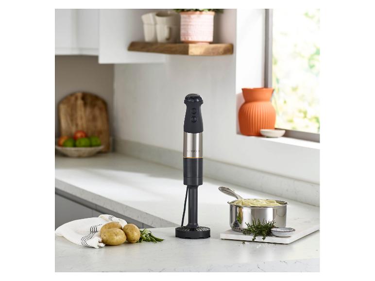 Staafmixer in een keuken met aardappelpuree, aardappelen en kruiden.