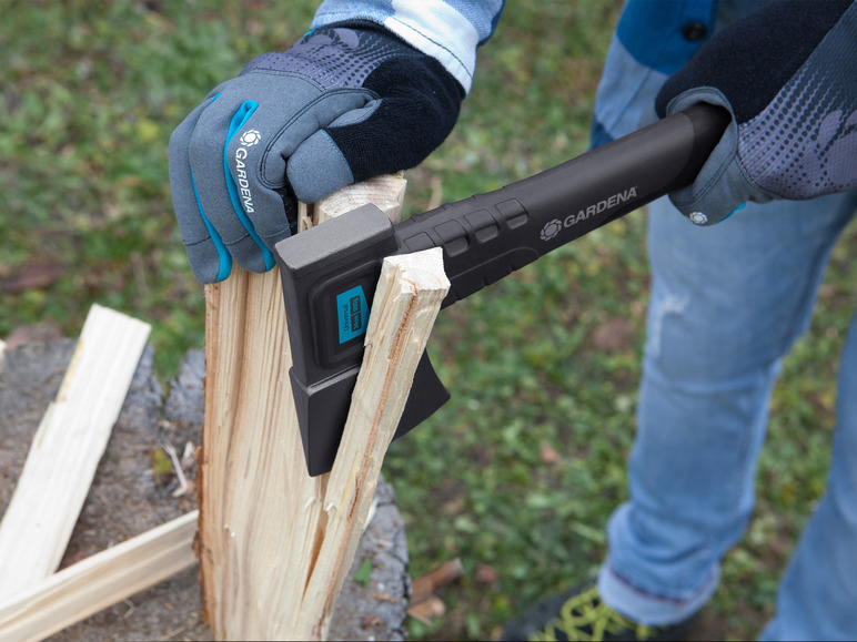 Een persoon gebruikt een Gardena bijl om hout te hakken.