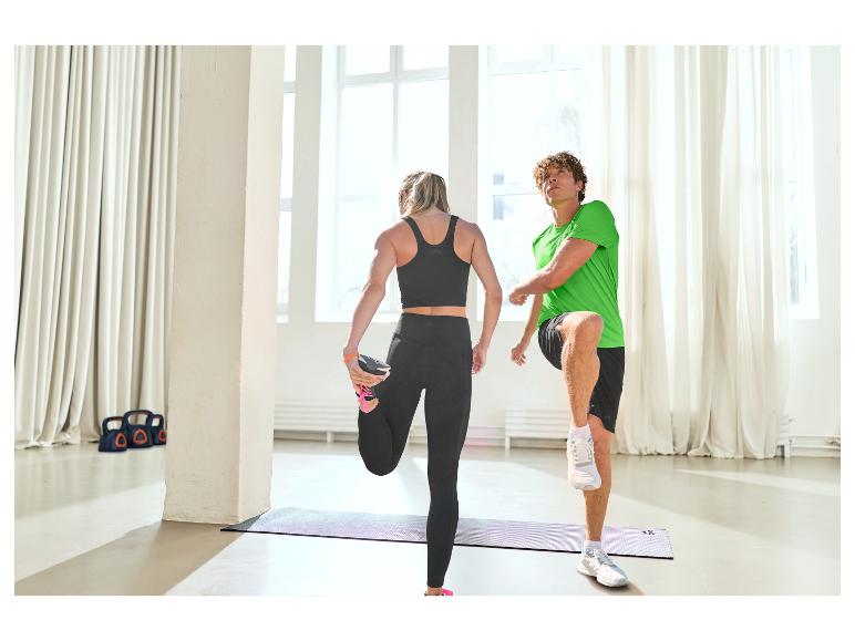 Twee mensen rekken zich uit op yogamatten in sportkleding.