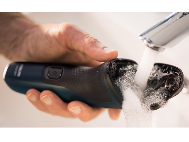 Un rasoir Philips est nettoyé sous l'eau courante.