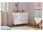 Commode blanche à trois tiroirs, décorée d'un vase doré et d'une bougie, près d'un rideau beige.