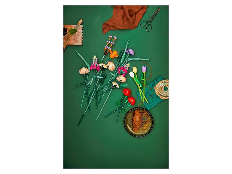 Des fleurs LEGO, dont des roses, des tulipes et d'autres fleurs, sont disposées sur un fond vert.