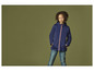 Een meisje draagt een blauwe softshell jas en een spijkerbroek.