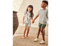 Twee kinderen dragen casual kleding en sneakers, terwijl ze hand in hand lopen.