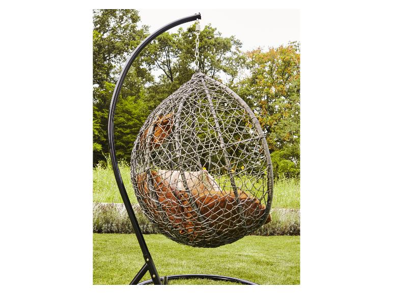 Fauteuil œuf avec coussins marrons dans un jardin