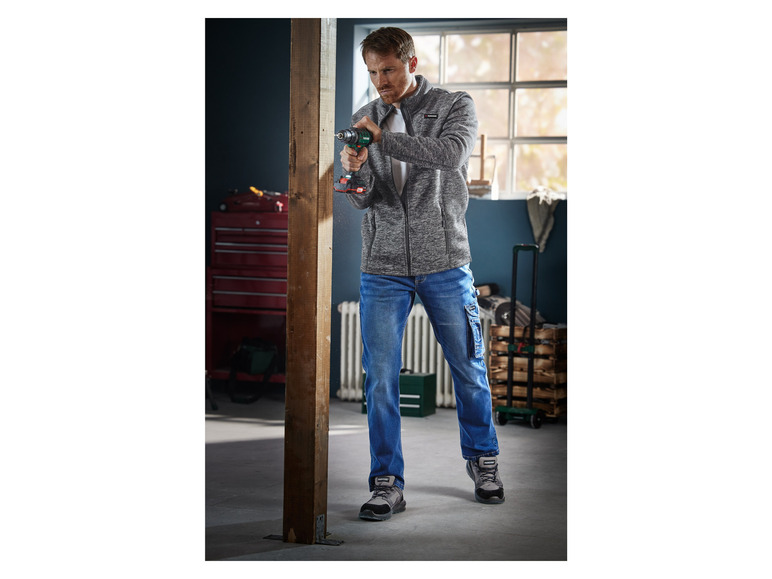 Un homme utilise une perceuse verte Parkside pour fixer un morceau de bois.